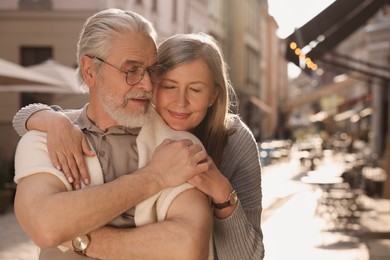 Affectionate senior couple walking outdoors, space for text