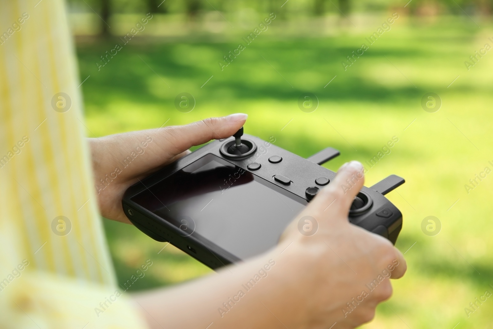 Photo of Woman holding new modern drone controller outdoors, closeup of hands