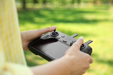 Photo of Woman holding new modern drone controller outdoors, closeup of hands