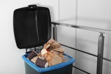 Photo of Trash bin full of garbage indoors. Waste recycling