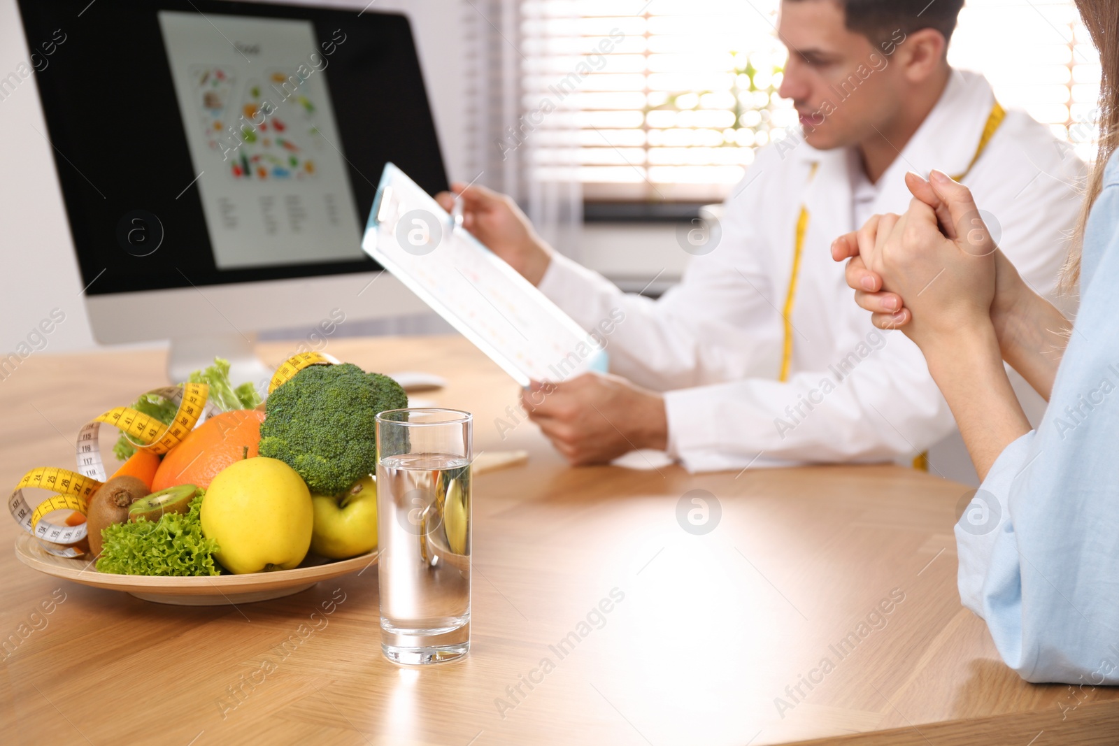 Photo of Nutritionist consulting patient at table in clinic, closeup