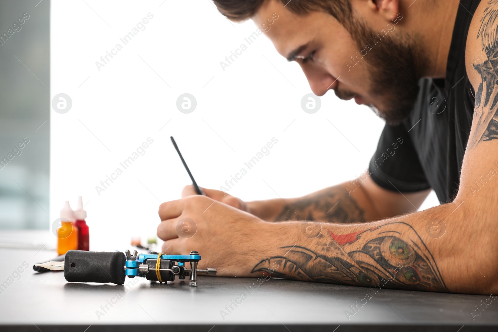 Photo of Professional tattoo artist drawing sketch at table indoors