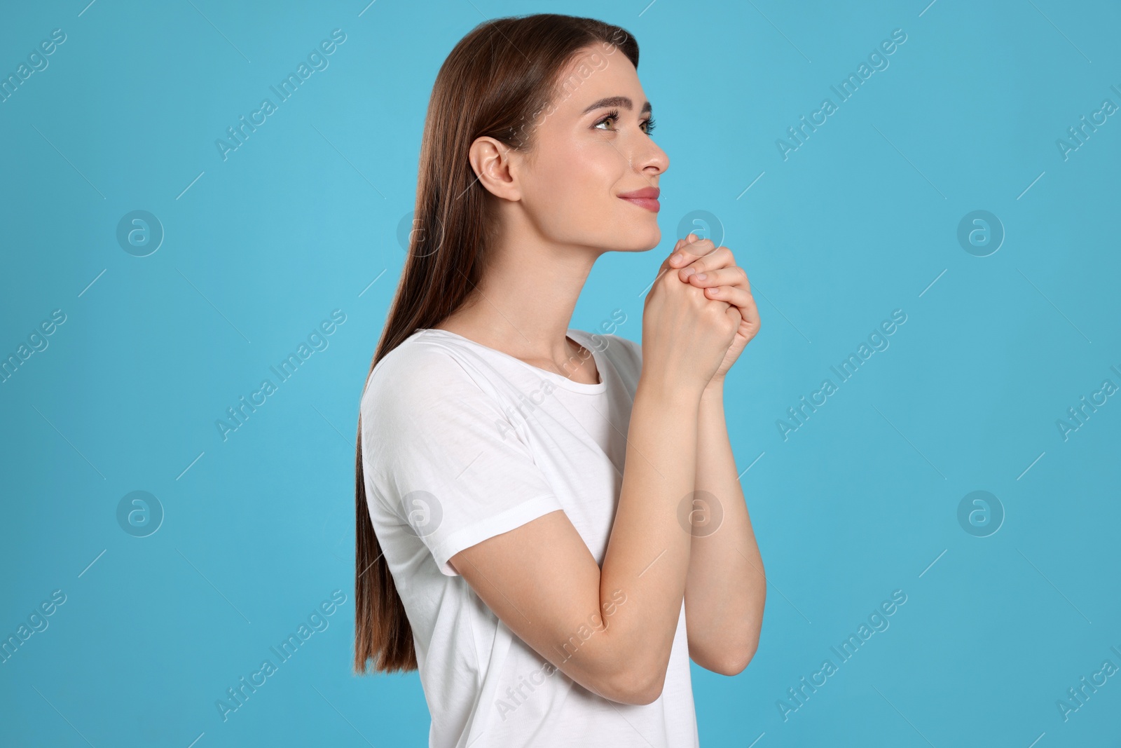 Photo of Woman with clasped hands praying on turquoise background