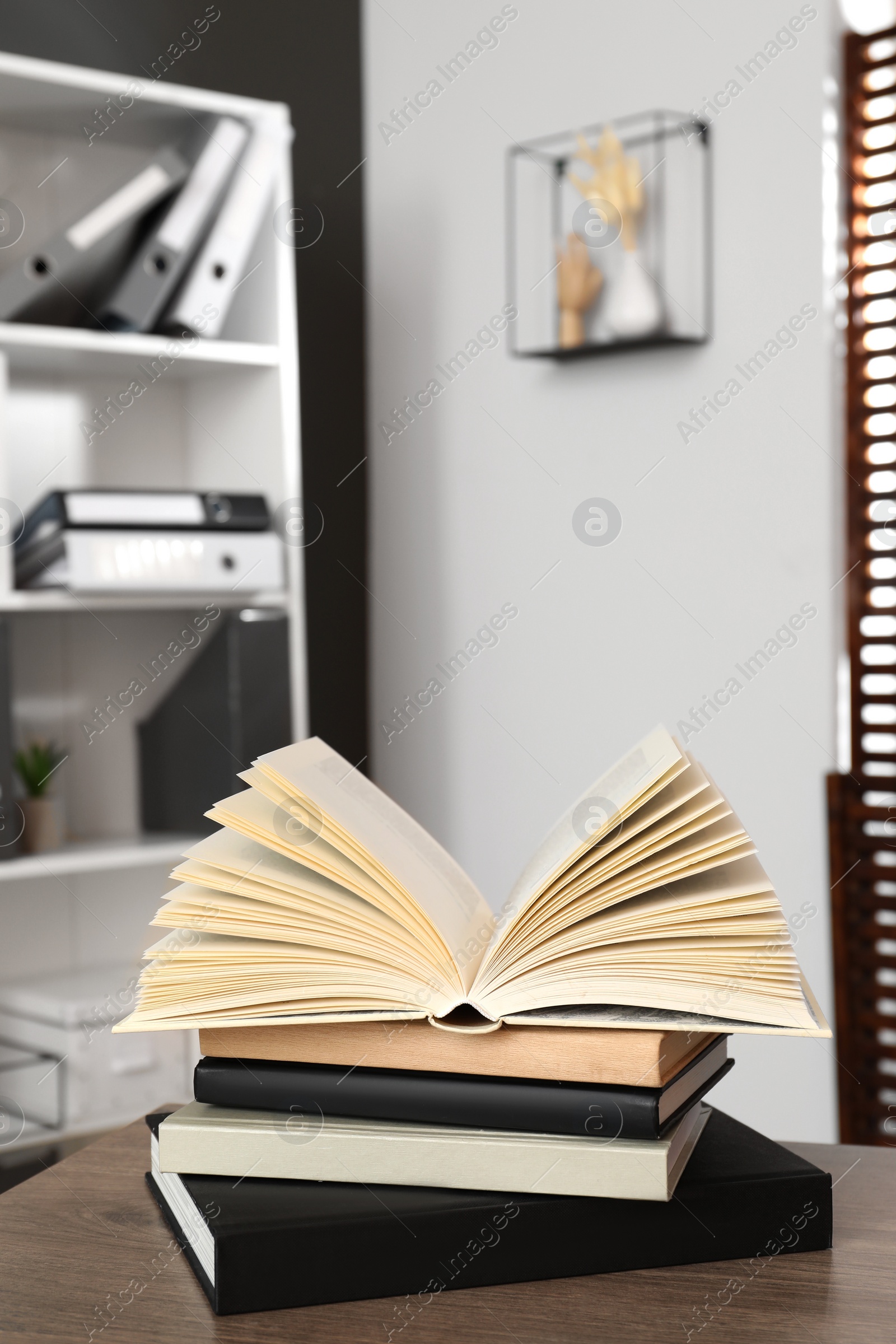 Photo of Stack of different hardcover books on wooden table indoors