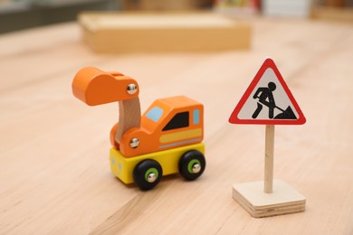 Photo of Miniature road sign and vehicle on wooden table, closeup. Montessori toy