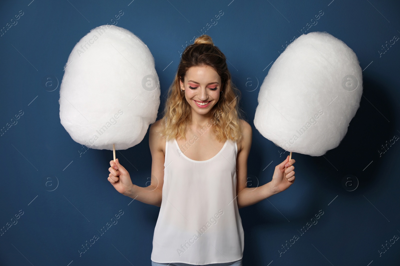 Photo of Portrait of pretty young woman with cotton candy on blue background