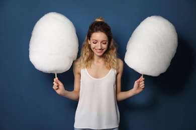 Photo of Portrait of pretty young woman with cotton candy on blue background