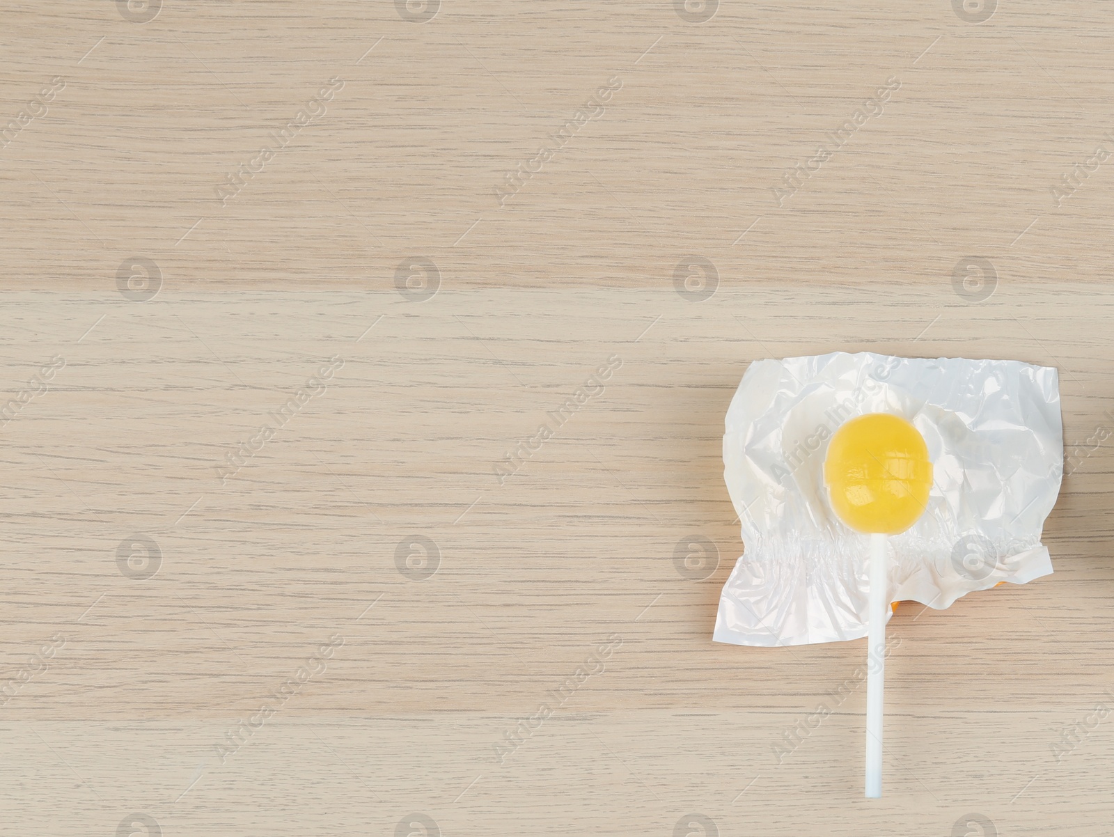 Photo of Lemon drops and lollipop on wooden table, flat lay. Space for text