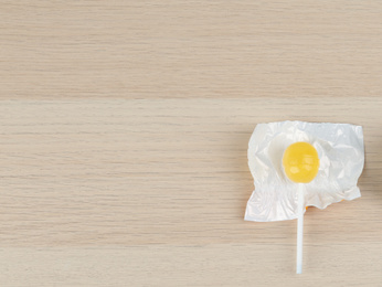 Photo of Lemon drops and lollipop on wooden table, flat lay. Space for text