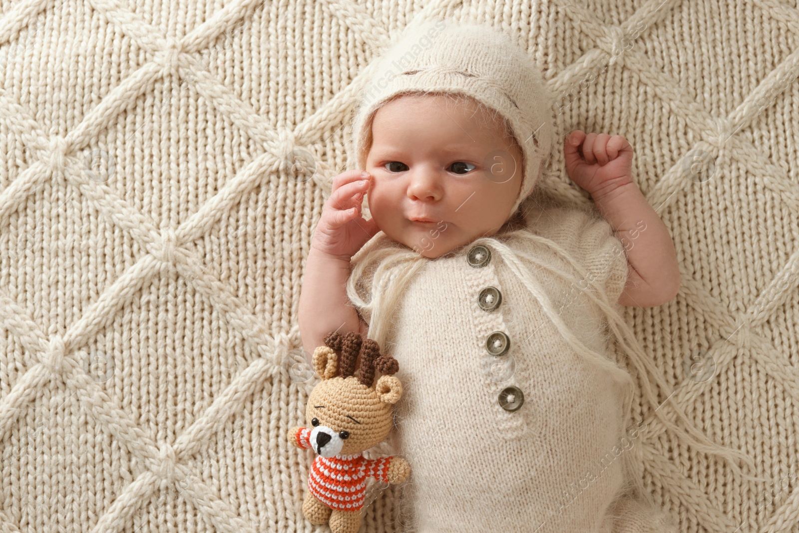 Photo of Adorable little baby with deer toy lying on blanket, top view. Space for text