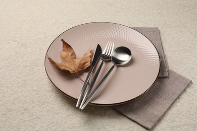 Stylish table setting with cutlery and dry leaf on light surface