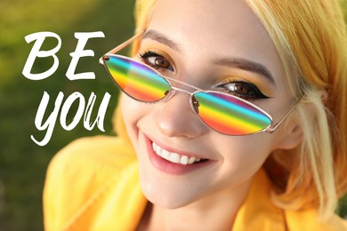 Image of Be You, coming out. Beautiful young woman in sunglasses with rainbow lenses on blurred green background, closeup
