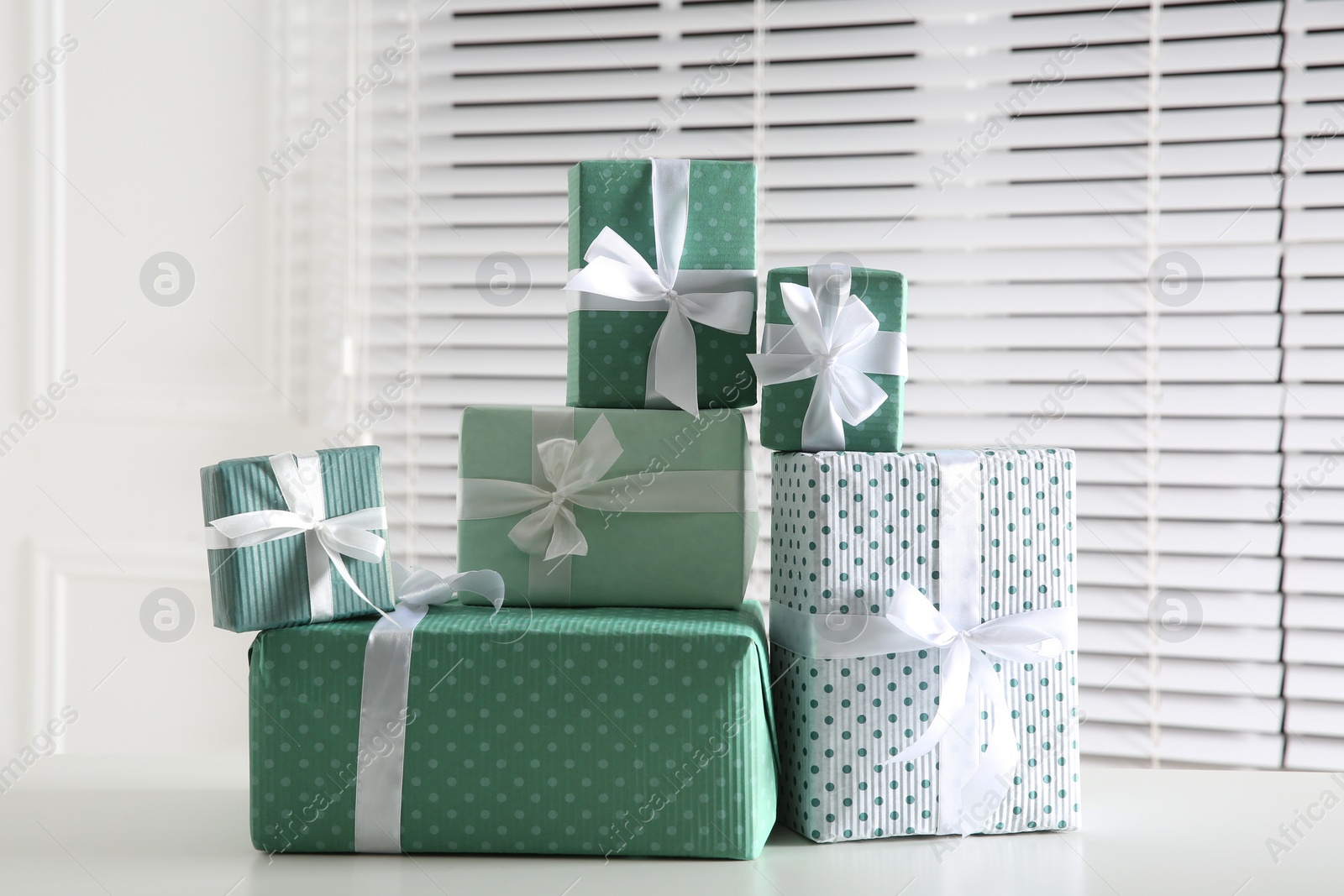 Photo of Heap of wrapped gift boxes on white table. Happy holiday