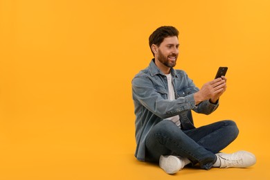 Photo of Happy man with smartphone on yellow background. Space for text