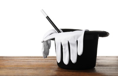 Photo of Magician's hat, gloves and wand on wooden table against white background