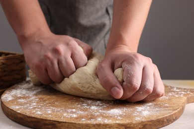 Photo of Man kneading dough at table near grey wall, closeup