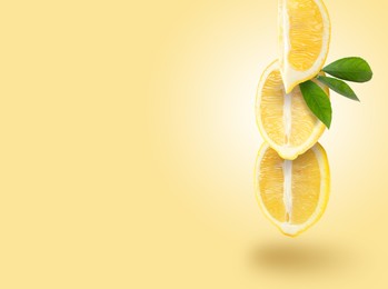 Fresh lemons with green leaves falling on pastel gold background, space for text