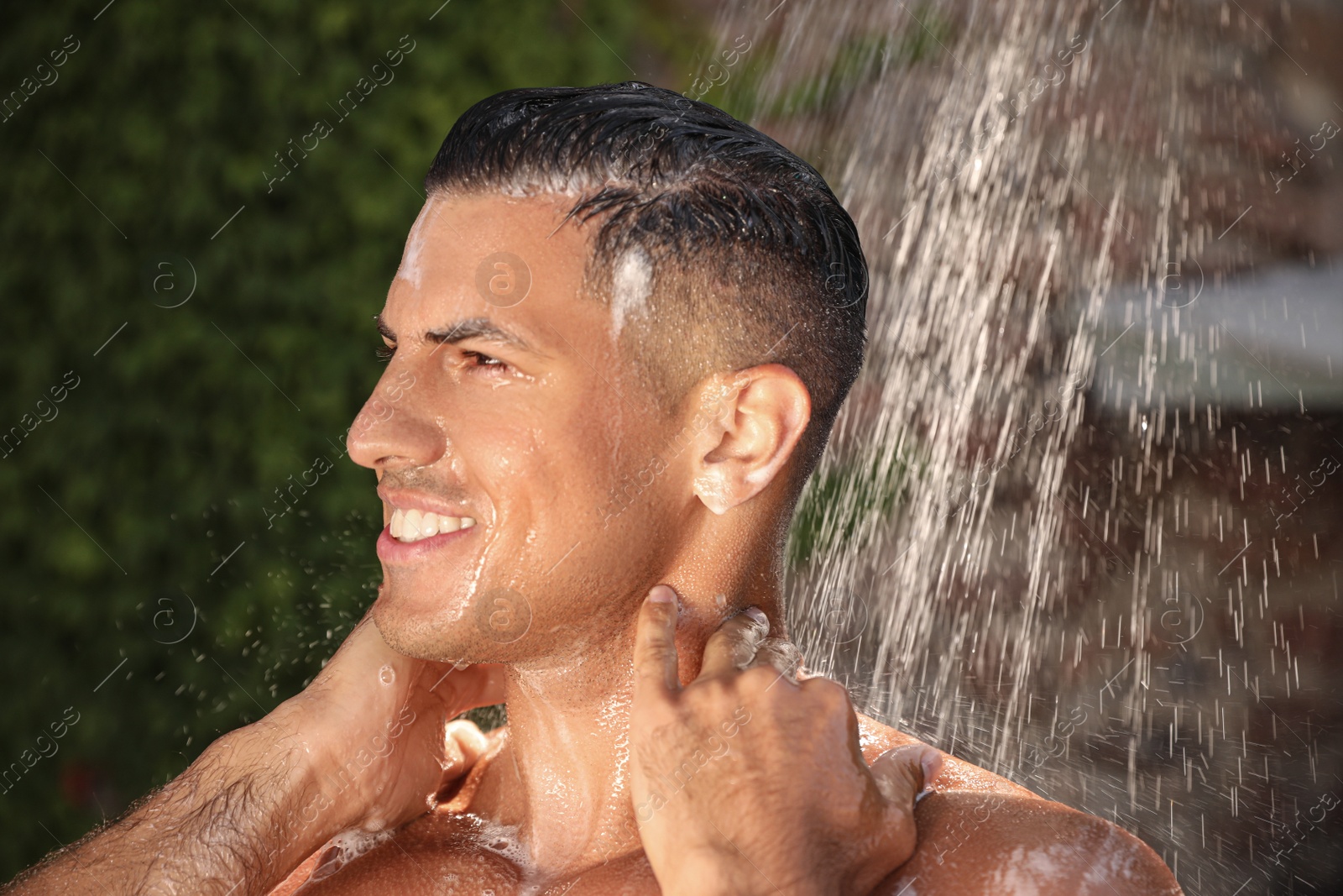 Photo of Man washing hair in outdoor shower on summer day, closeup