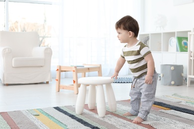 Cute baby holding on to stool at home.  Learning to walk