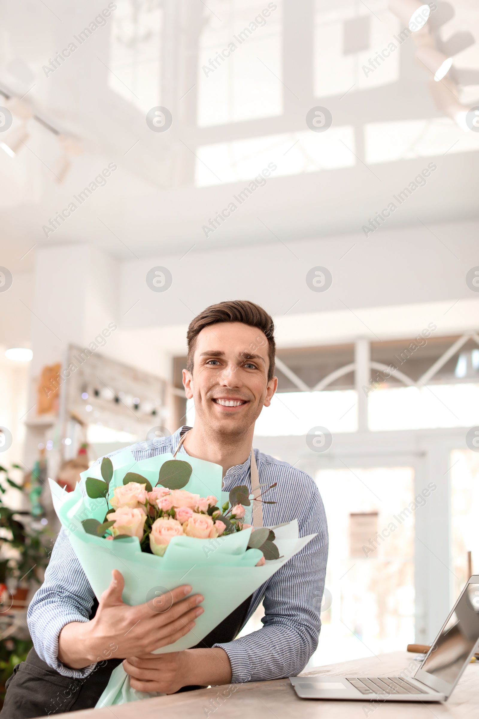 Photo of Male florist holding bouquet flowers at workplace
