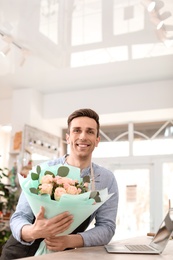 Male florist holding bouquet flowers at workplace