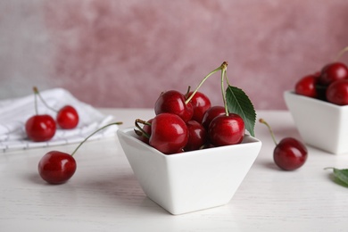 Photo of Bowl with ripe sweet cherries on white wooden table