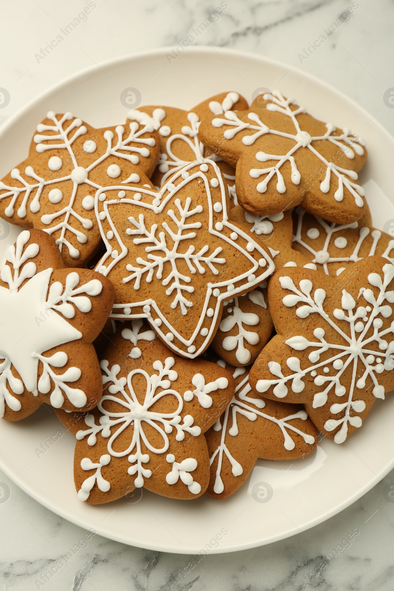 Photo of Tasty star shaped Christmas cookies with icing on white marble table, top view