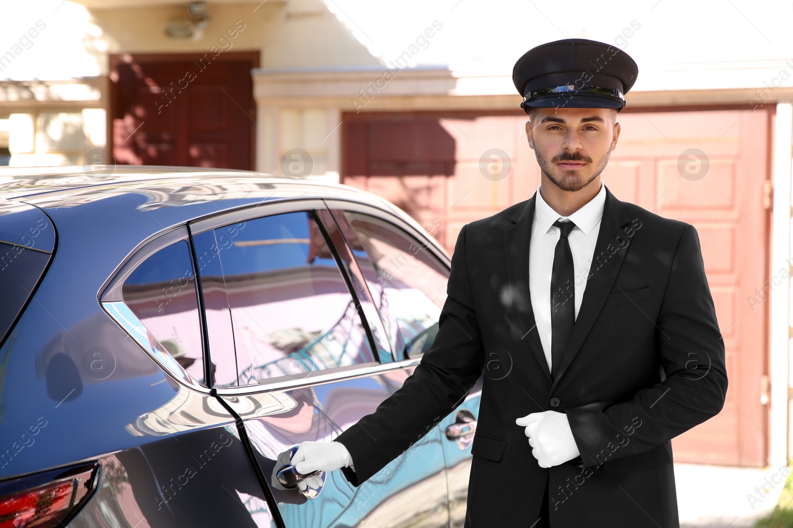 Photo of Young handsome driver standing near luxury car. Chauffeur service