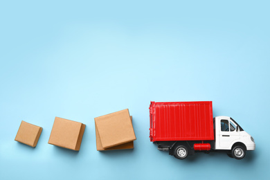 Photo of Top view of toy truck with boxes on blue background. Logistics and wholesale concept