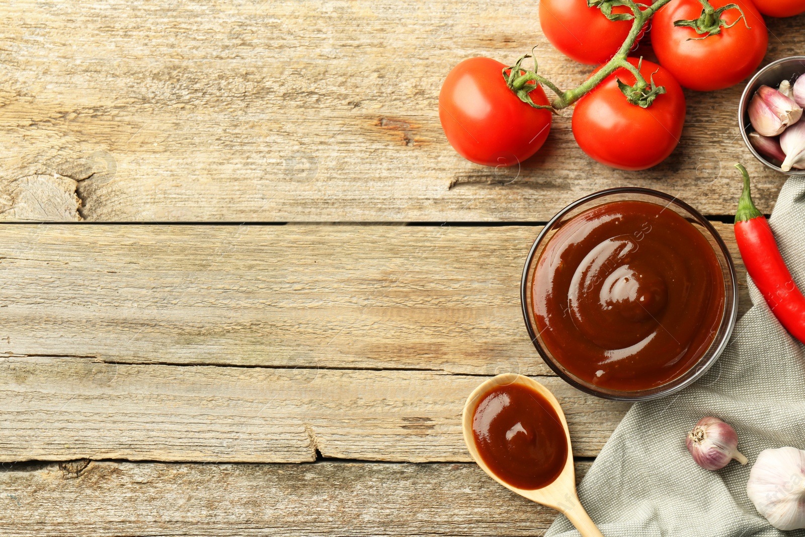 Photo of Flat lay composition with tasty barbeque sauce in bowl on wooden table. Space for text