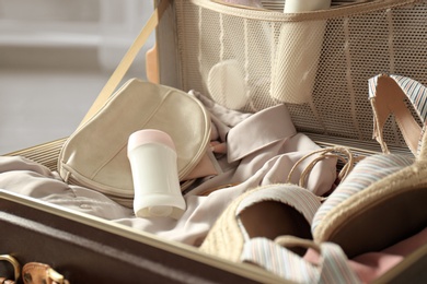 Photo of Vintage suitcase with deodorants and clothes at home, closeup view