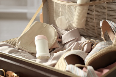 Vintage suitcase with deodorants and clothes at home, closeup view