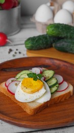 Tasty sandwich with boiled egg, radish and cucumber on light grey table