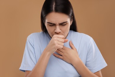 Photo of Woman coughing on brown background. Cold symptoms