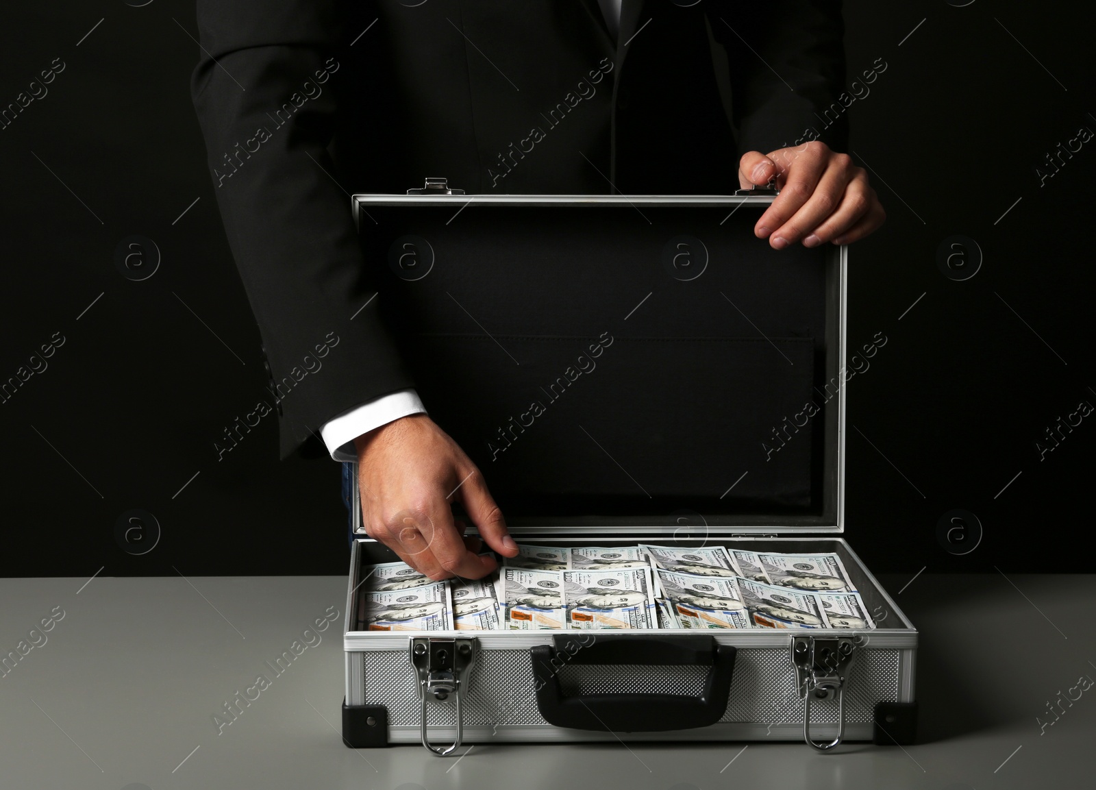 Photo of Businessman with suitcase full of money on dark background