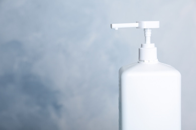 Photo of Dispenser bottle with antiseptic gel on light background, closeup. Space for text