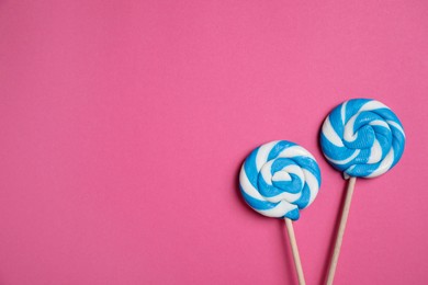 Sticks with bright lollipops on pink background, flat lay. Space for text