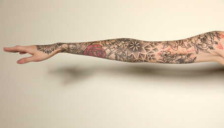 Photo of Woman with colorful tattoos on arm against white background, closeup