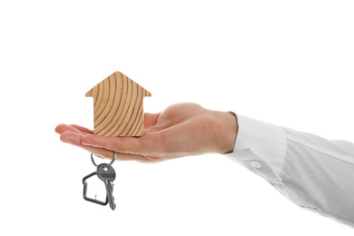 Photo of Real estate agent holding house figure and key on white background, closeup