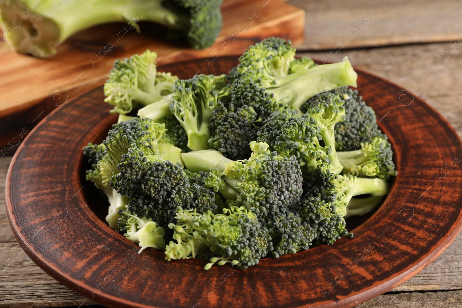 Photo of Plate with fresh raw broccoli on wooden table, closeup