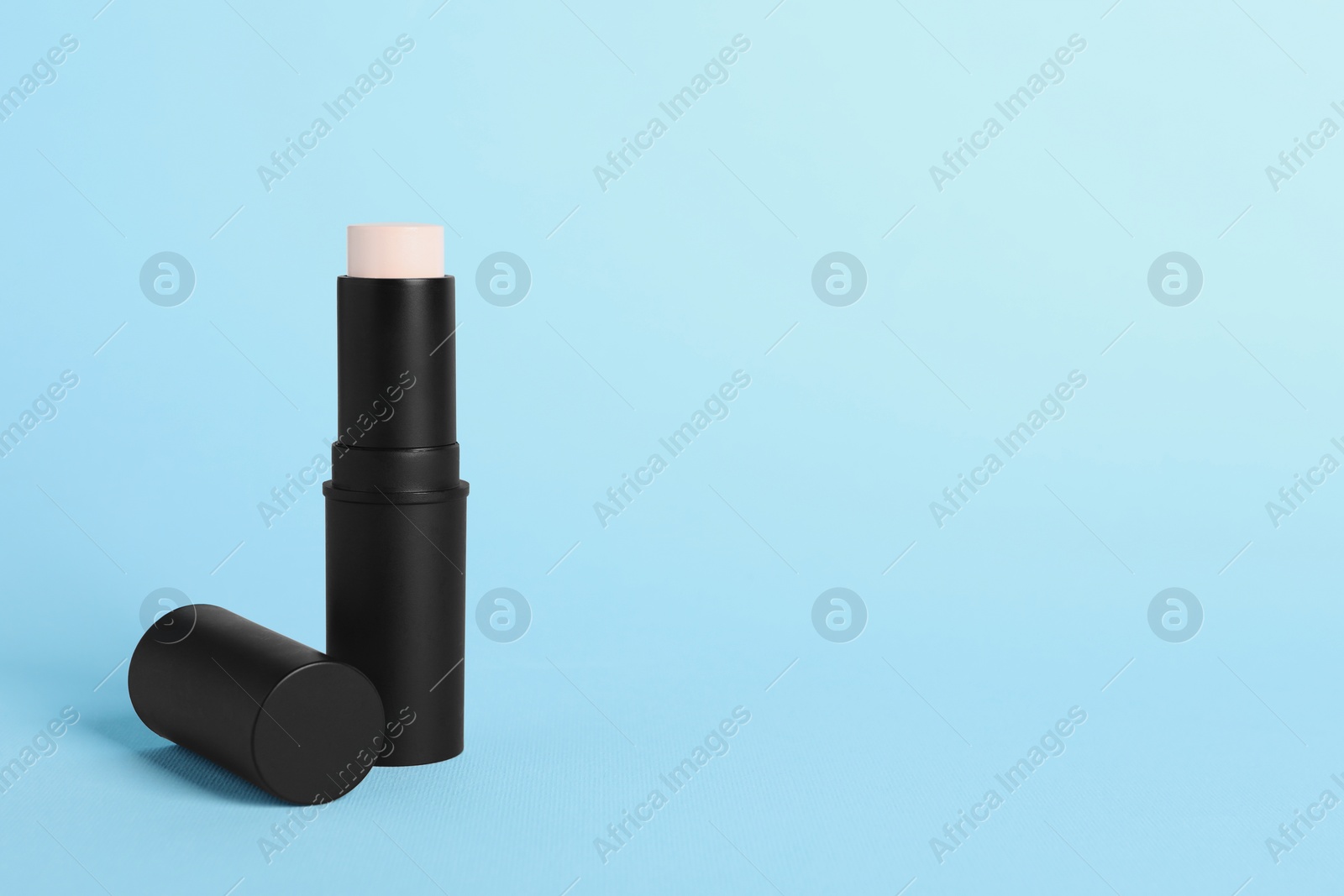 Photo of Stick foundation and on light blue background, space for text. Makeup product