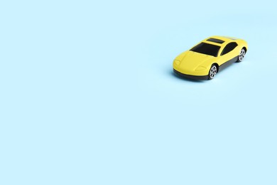 One yellow car on light blue background, space for text. Children`s toy
