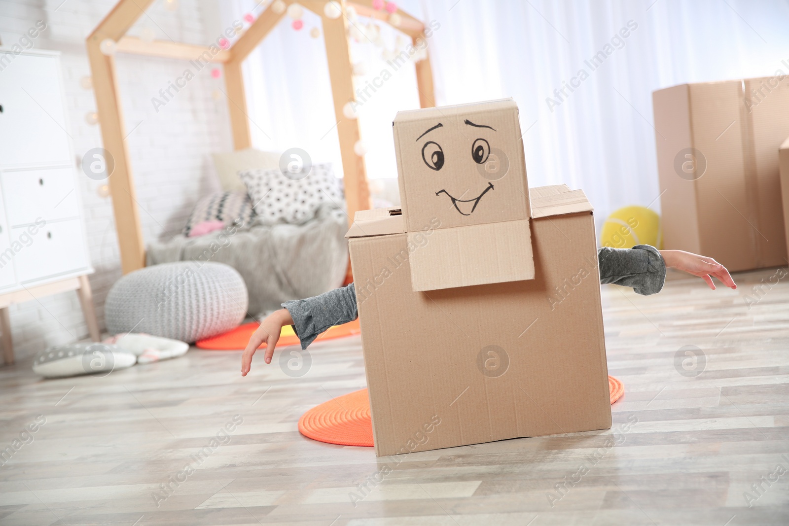 Photo of Cute little child wearing cardboard costume in bedroom