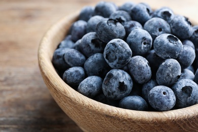 Photo of Tasty frozen blueberries in wooden bowl, closeup