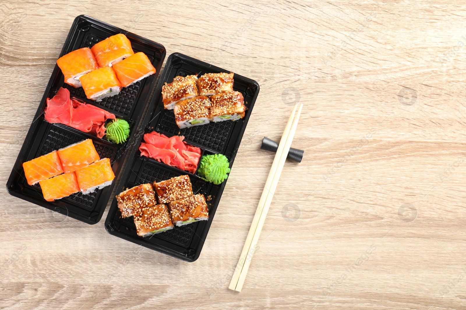 Photo of Tasty sushi rolls served on wooden table, top view with space for text. Food delivery