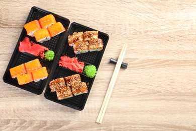 Tasty sushi rolls served on wooden table, top view with space for text. Food delivery