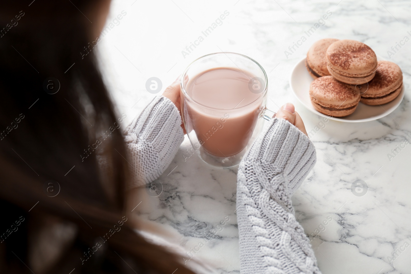 Photo of Young woman with delicious hot cocoa drink at table