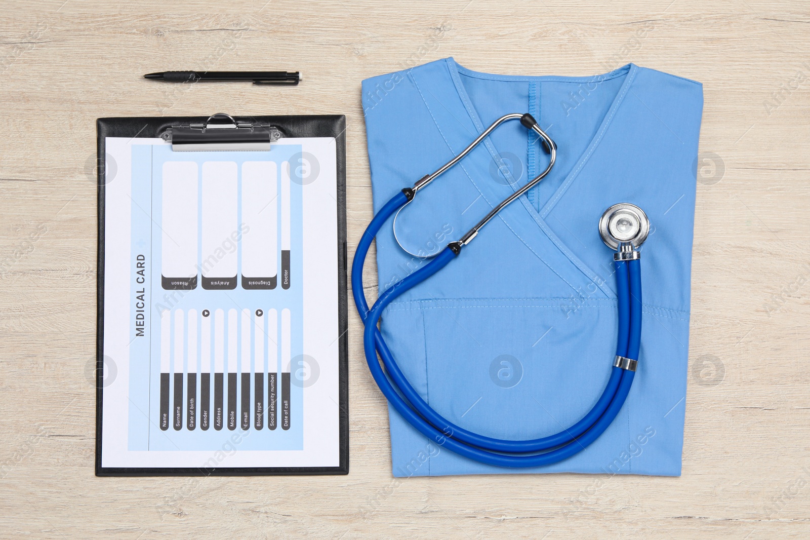 Photo of Medical uniform, stethoscope, clipboard and pen on light wooden table, flat lay