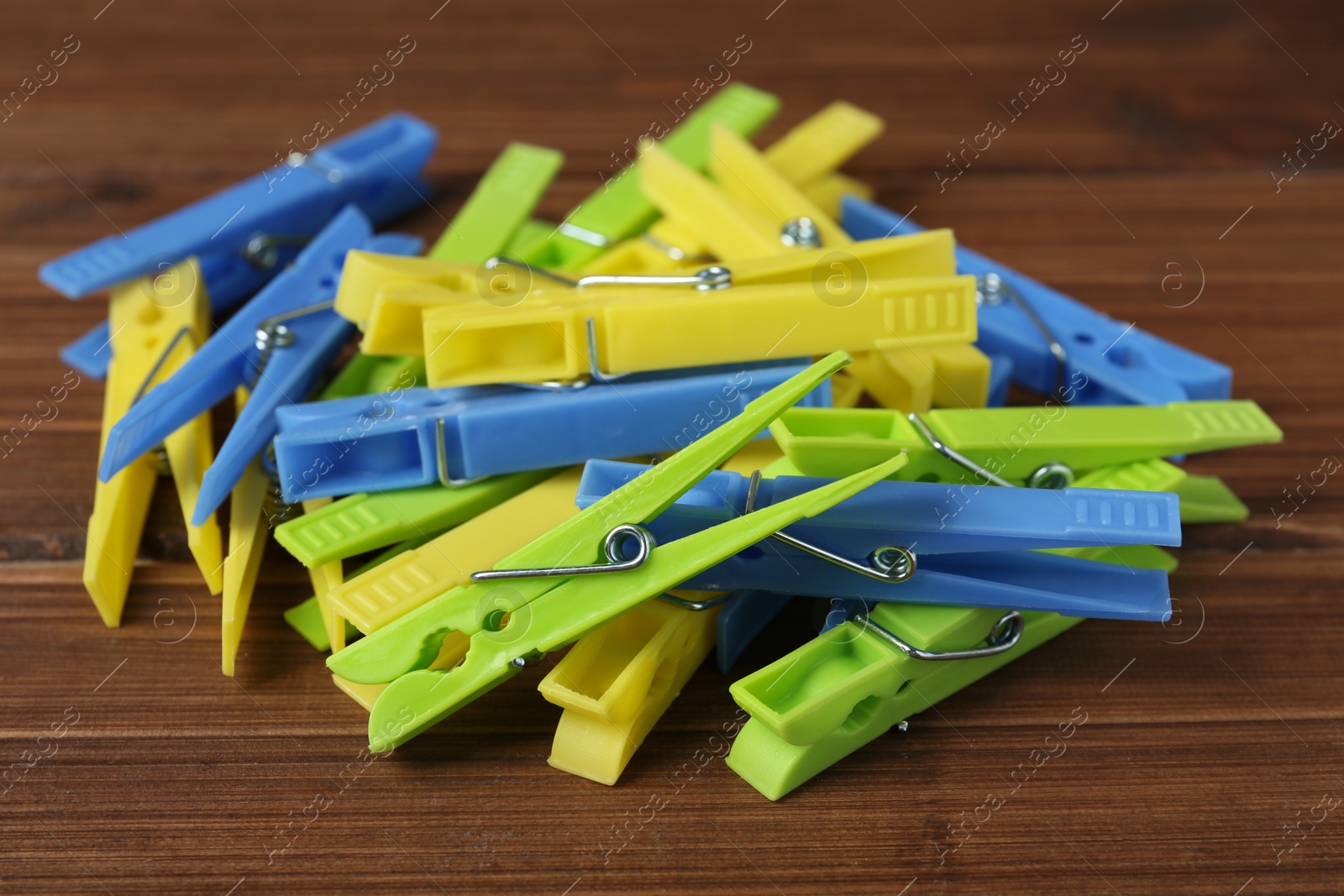 Photo of Pile of colorful plastic clothespins on wooden table, closeup