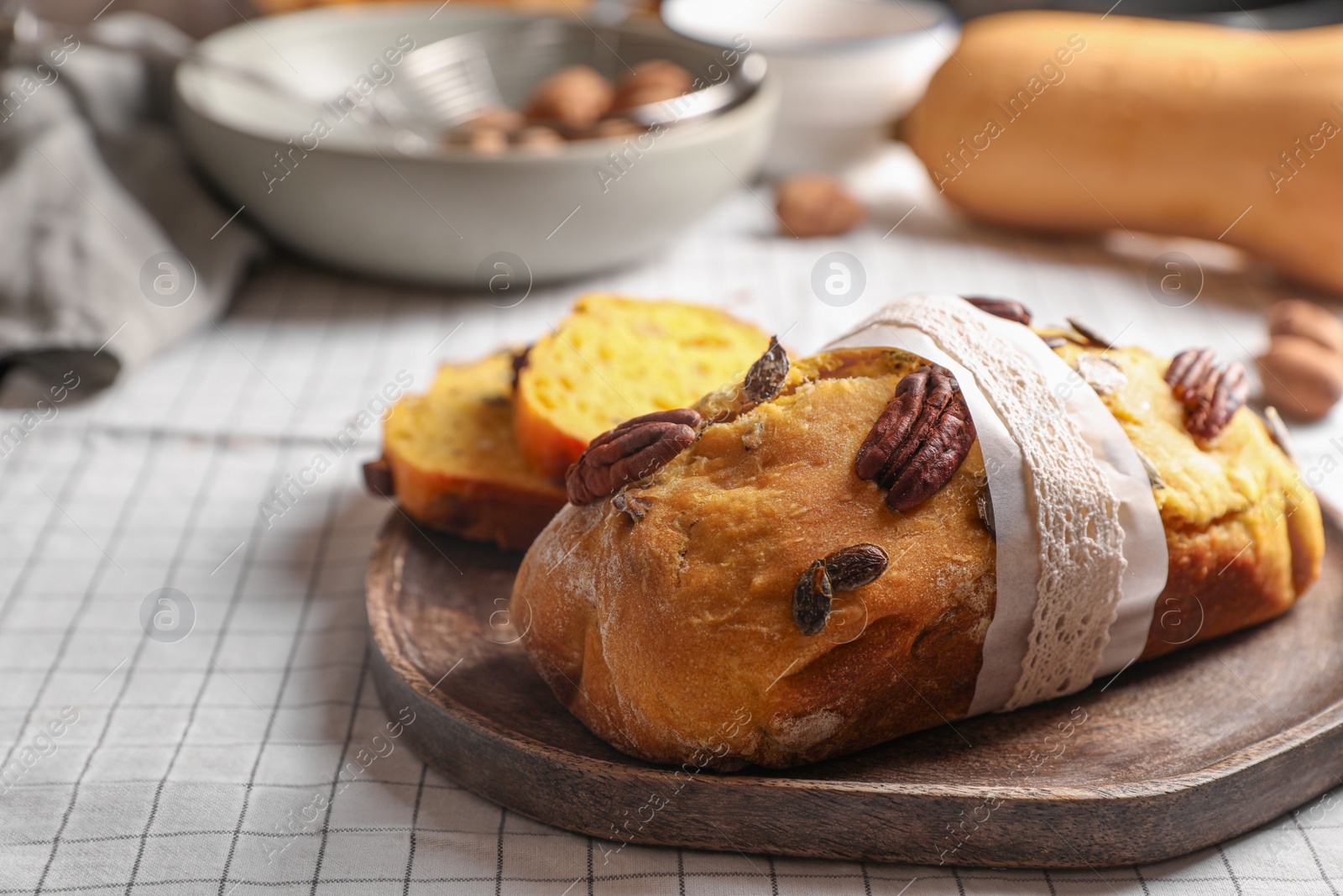 Photo of Delicious pumpkin bread with pecan nuts on tablecloth